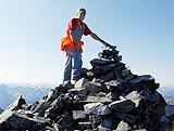 A hiker stands at the top of Perkins Peak at the cairn.
